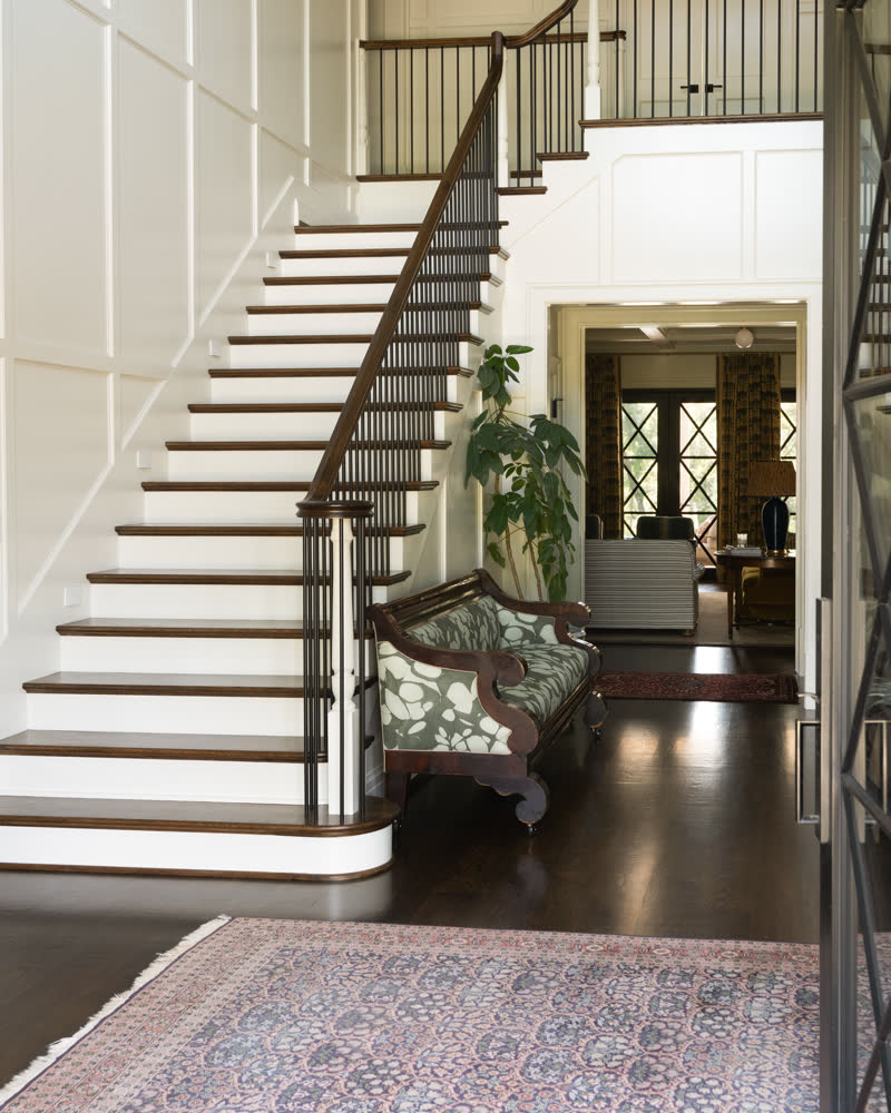A two-story entry hall with a curved staircase and dark hardwood floors.